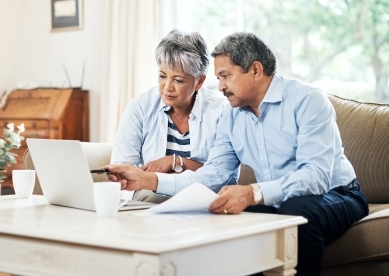 Couple sitting on their couch looking at paperwork on their coffee table
